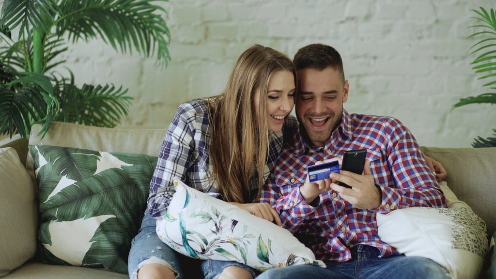 Two people reviewing a bank card and phone together, illustrating a UAE joint bank account