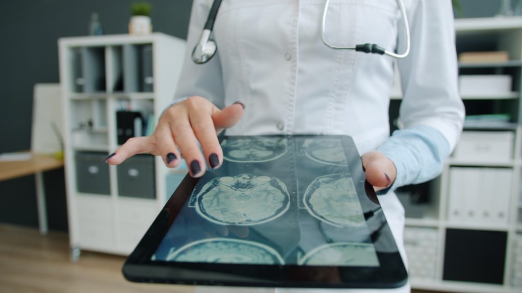 Clinician reviewing a patient's medical imaging on a tablet, illustrating who can access health records in the UAE