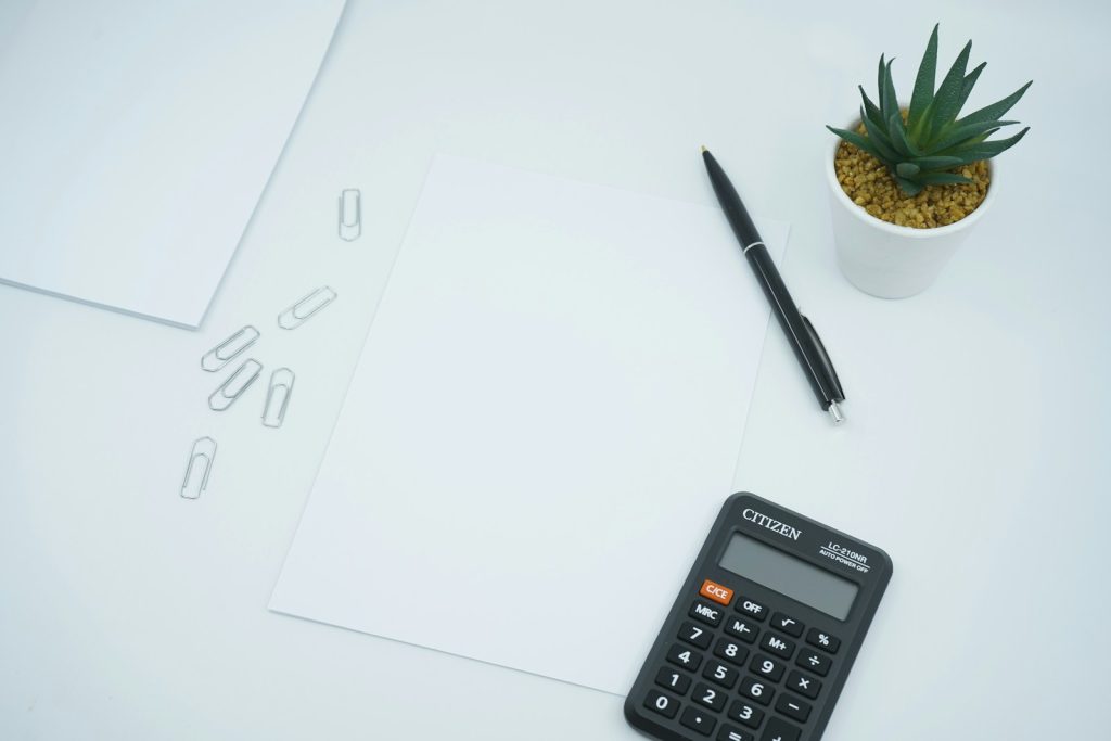 Blank document, pen and calculator on a desk, illustrating the process of ceasing South African tax residency from the UAE