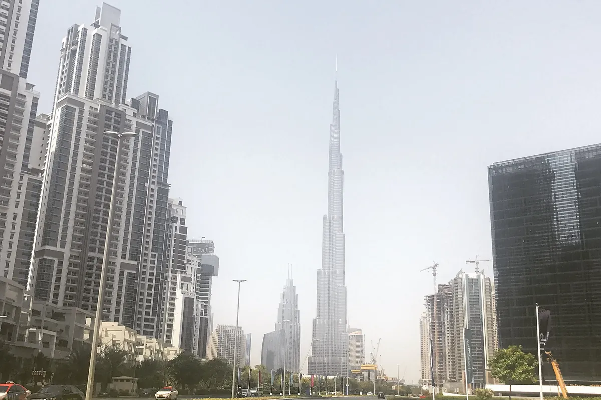 Street in Business Bay, Dubai, lined with high-rise towers leading toward Burj Khalifa