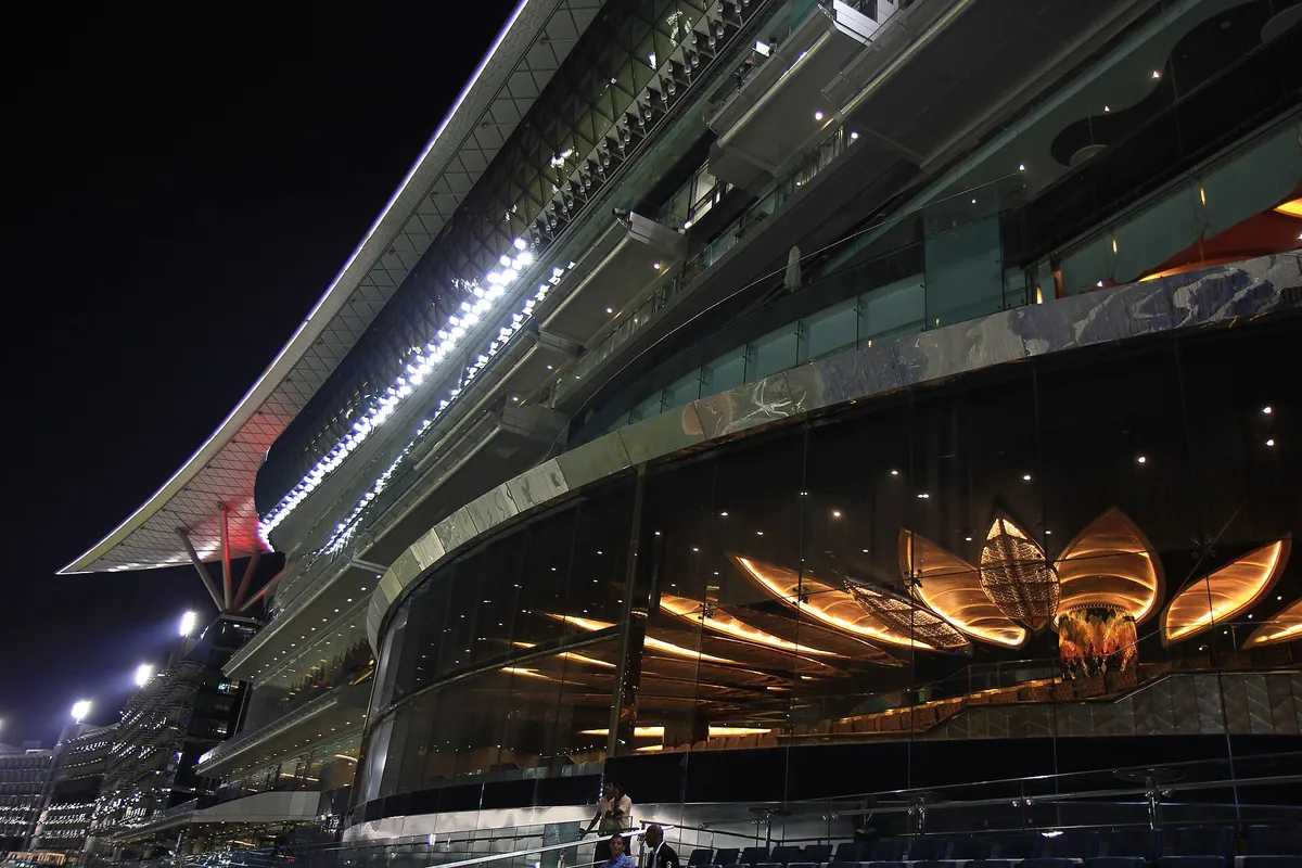 Meydan Racecourse grandstand lit up at night in Dubai's Meydan district